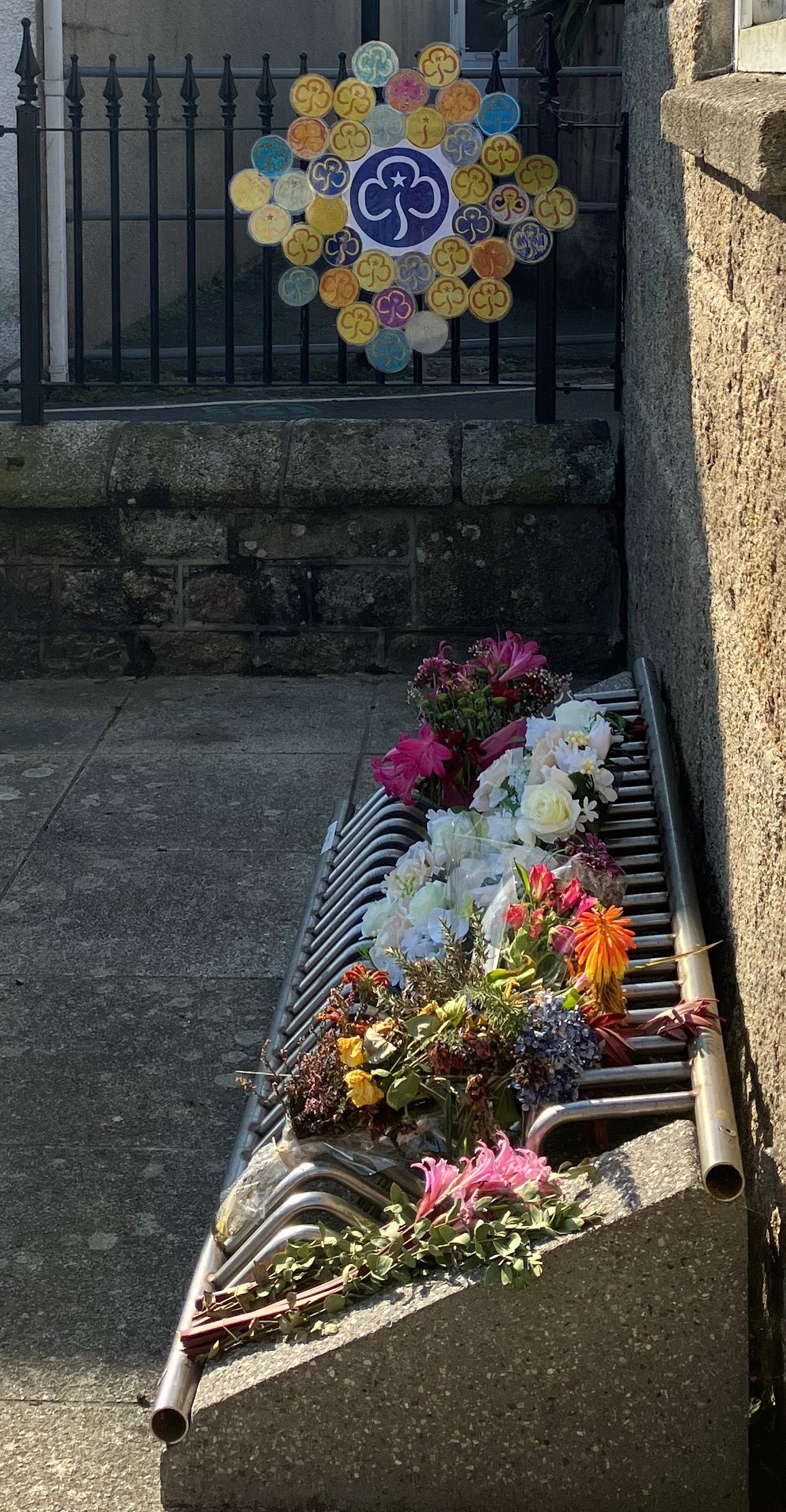 Image of a wreath made by the Brownies and floral tributes outside the Wesleyan Chapel on St Mary's