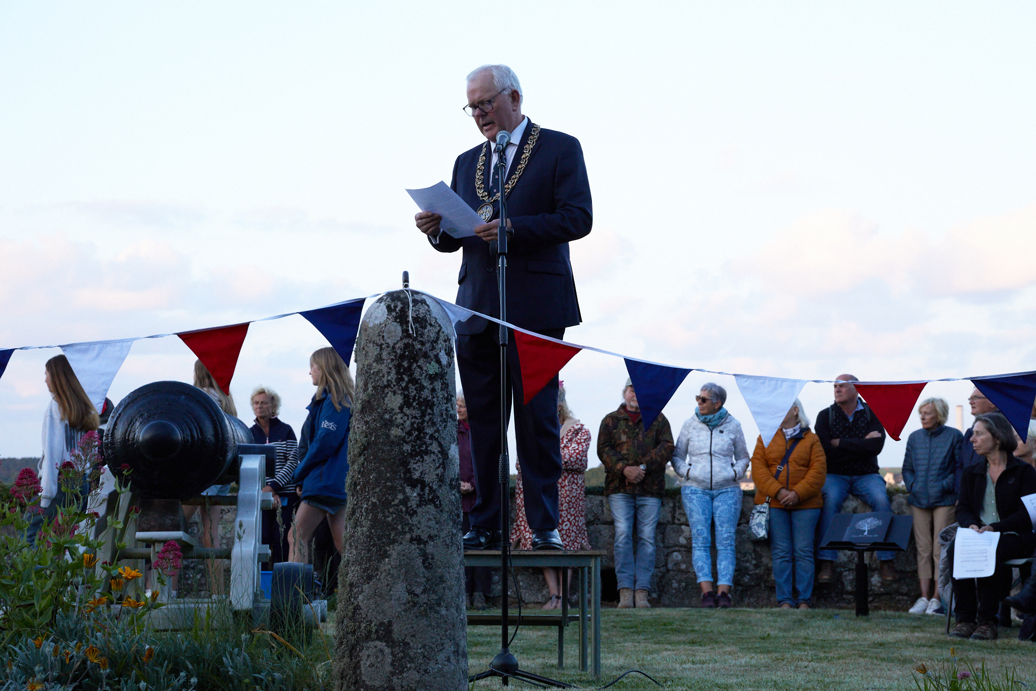 Photo of Cllr Robert Francis, Chairman of the Council of the Isles of Scilly reading the Proclamation at the D-Day 80th Anniversary commemoration ceremony in the garden at Hugh House, which overlooks Hugh Town, St Mary's.
