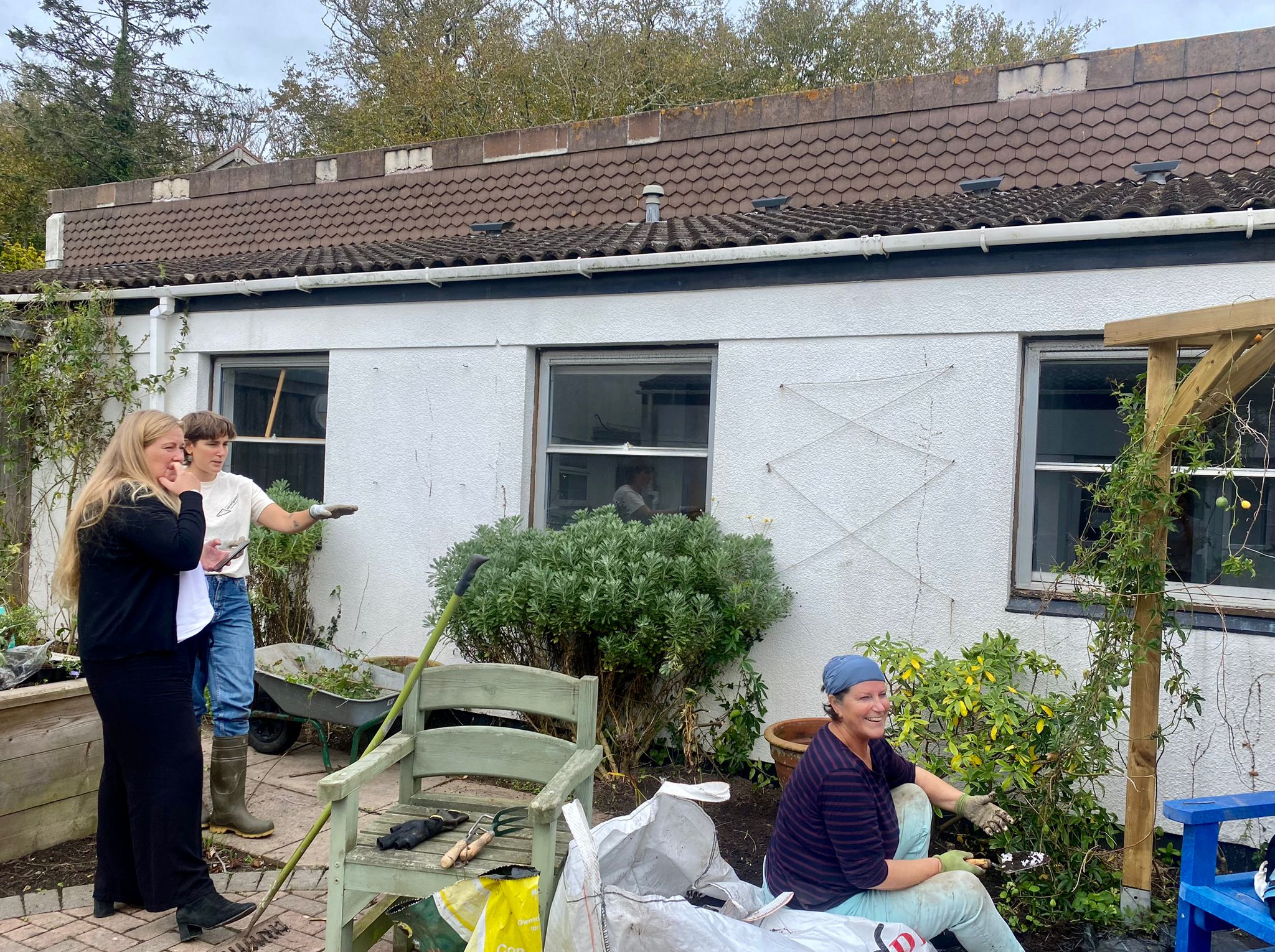 Image of local artist Maxine Cole and Children Services Assistant, Tamasin Bridge working with a volunteer to transform the courtyard at the Carn Gwaval Wellbeing Centre into the Community Garden