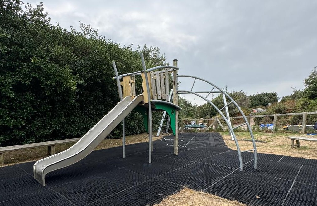Image of the repaired play equipment at the play park outside Bryher Community Centre, including a climbing frame and a swing
